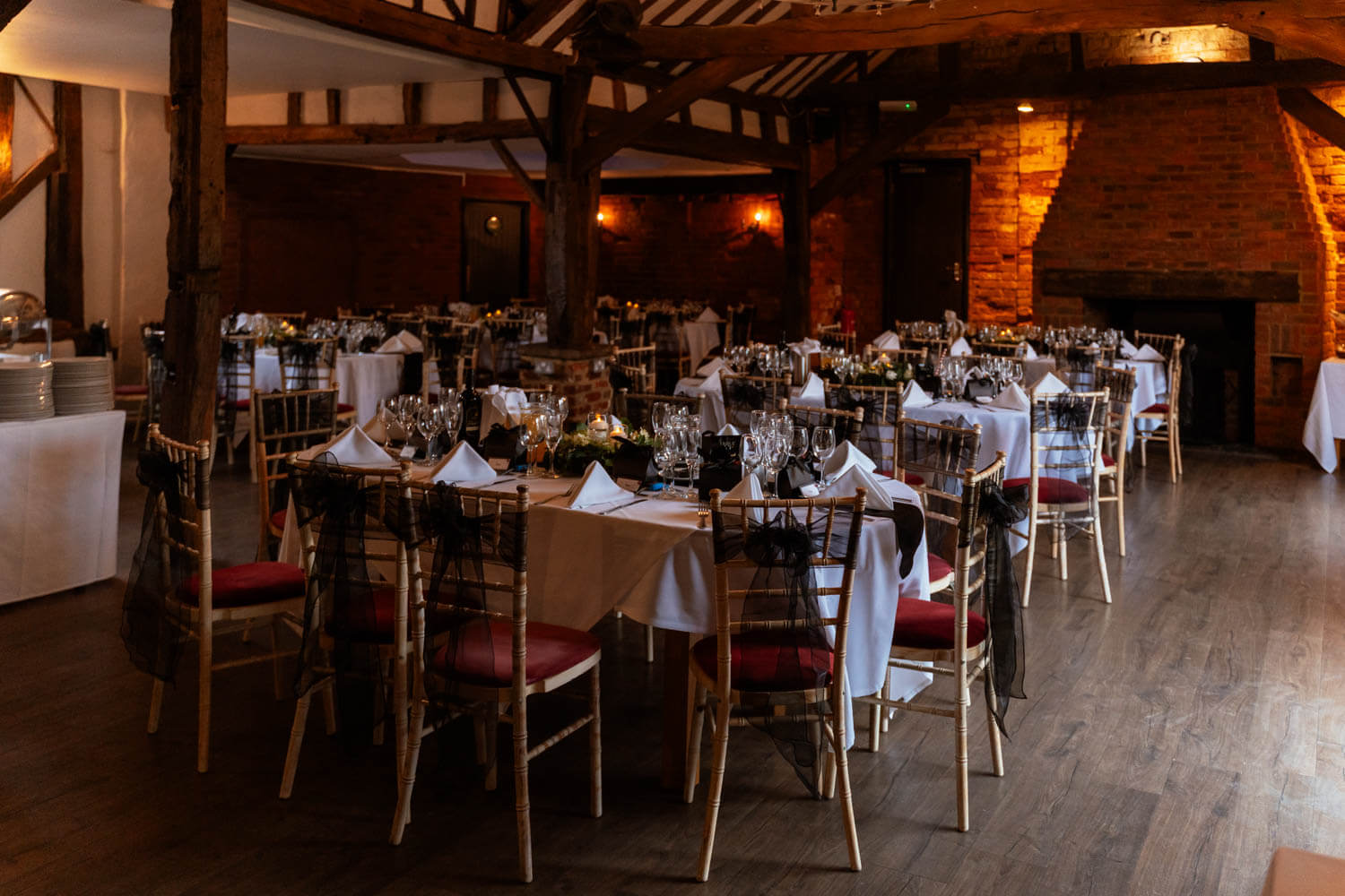 the Briar barn at Cantley house hotel is set for a wedding breakfast with black sashes on the chairs and floating candles in the cream and green floral centrepieces