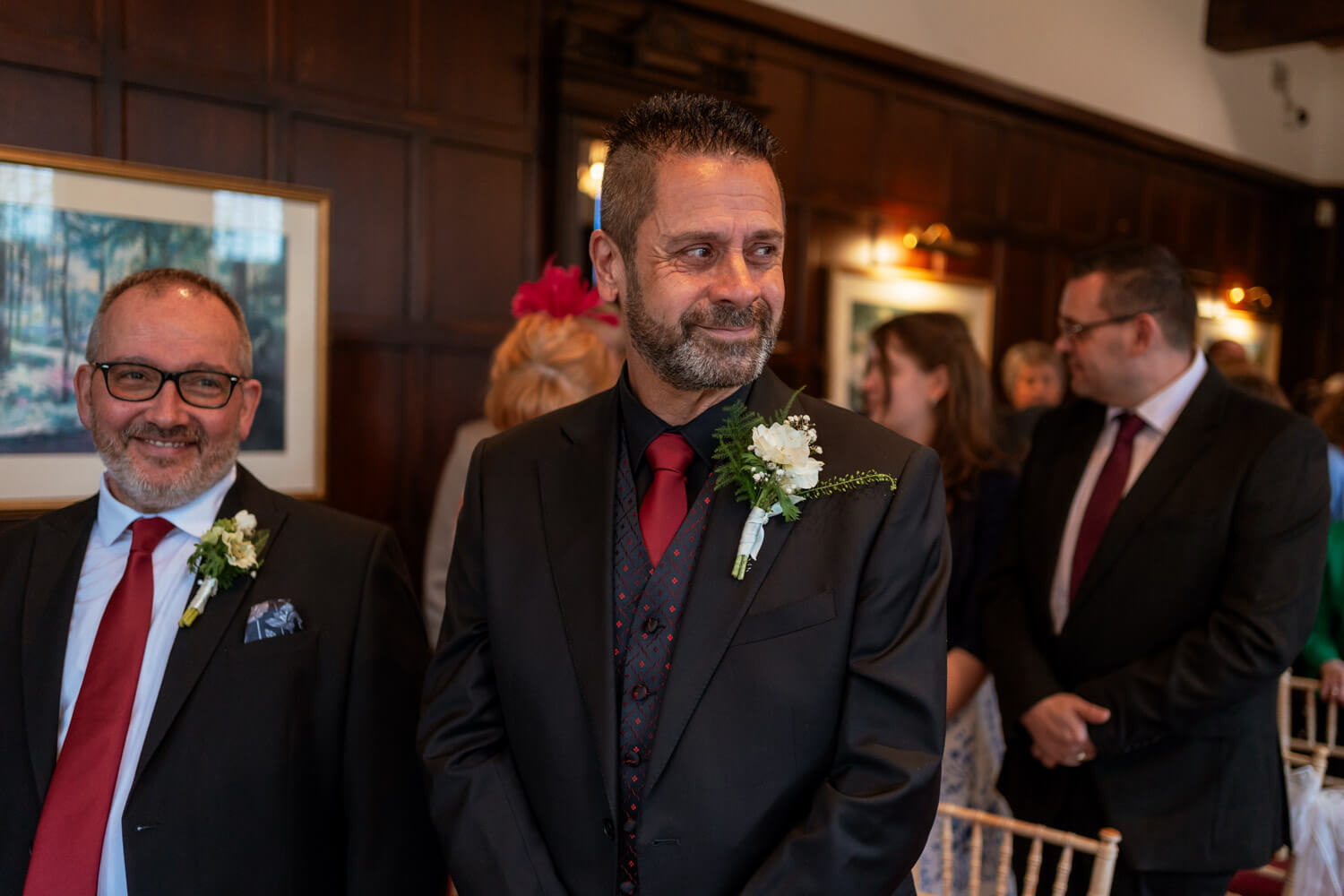 the smiling groom, flanked by his best man stand at the top of the aisle just before the entrance of the bride