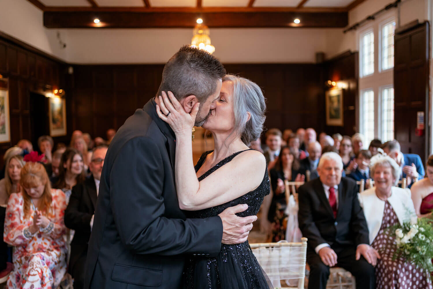 the bride and groom share a first kiss during the wedding ceremony in the Oak Room at Cantley House