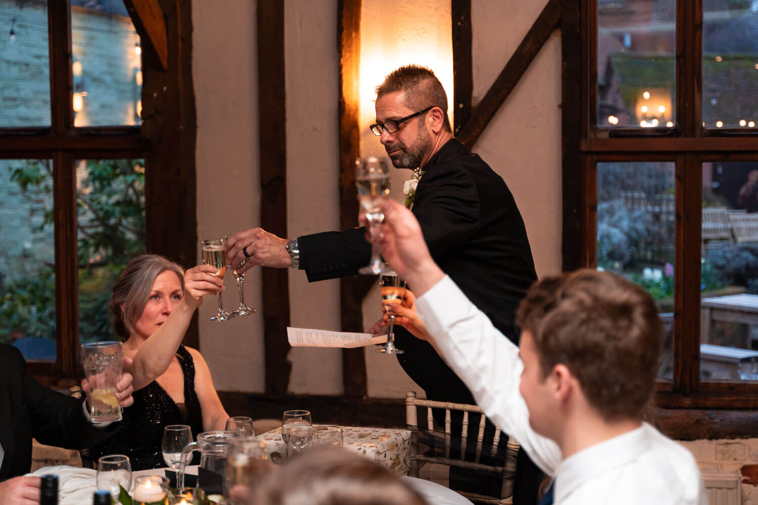 the bride and groom surrounded by wedding guests propose a toast