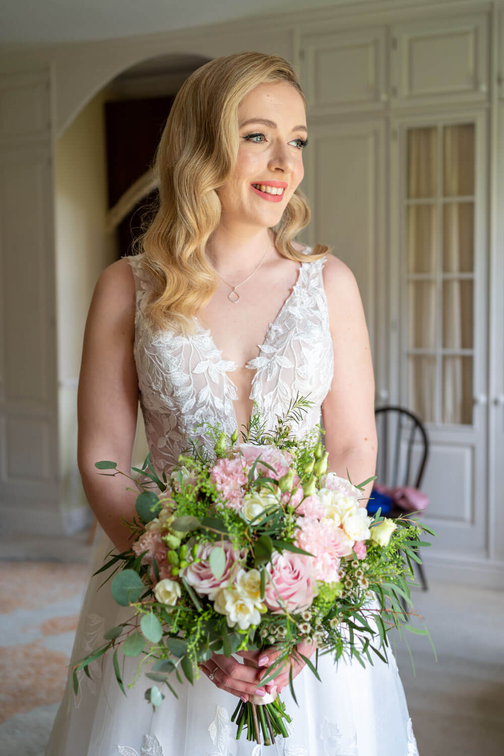 the bride holds her bouquet as she looks out of the window at Herons farm
