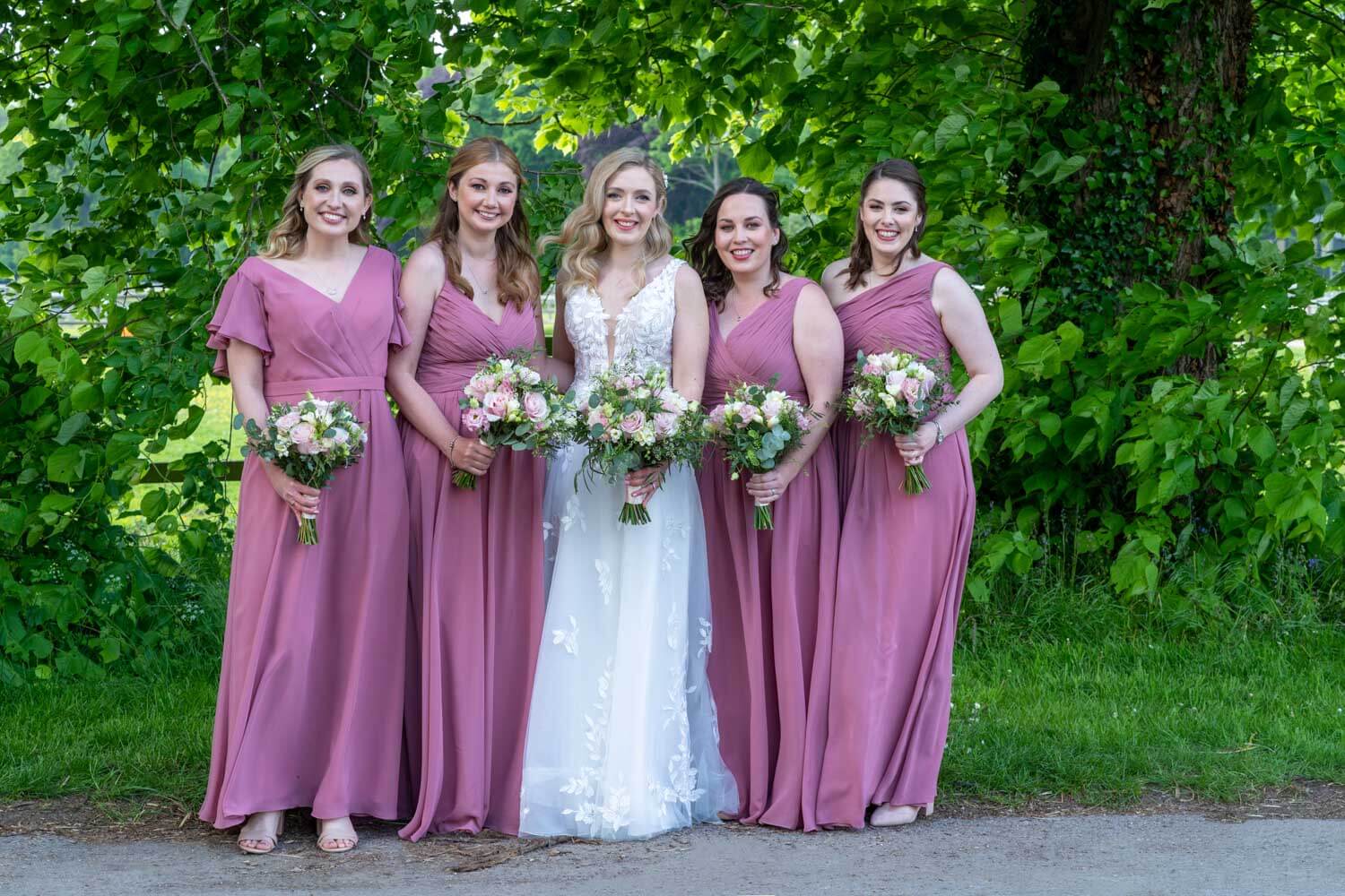 the bride flanked by two bridesmaids in dark pink dresses on each side