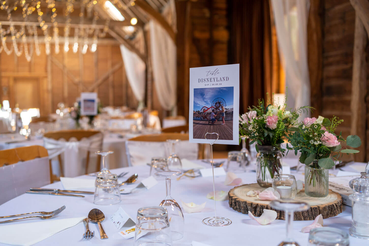 a wedding breakfast detail, a photo of the couple and two jam jars with pink and white flowers and greenery