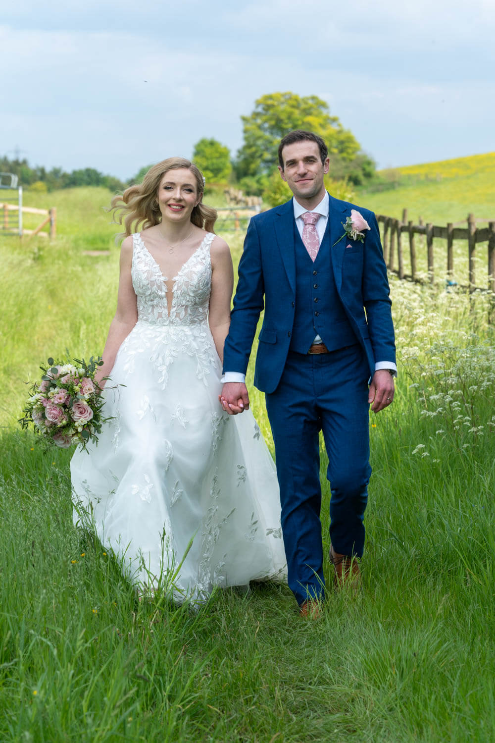 the bride and groom walk briskly along the grass track on the Gallops at Herons farm