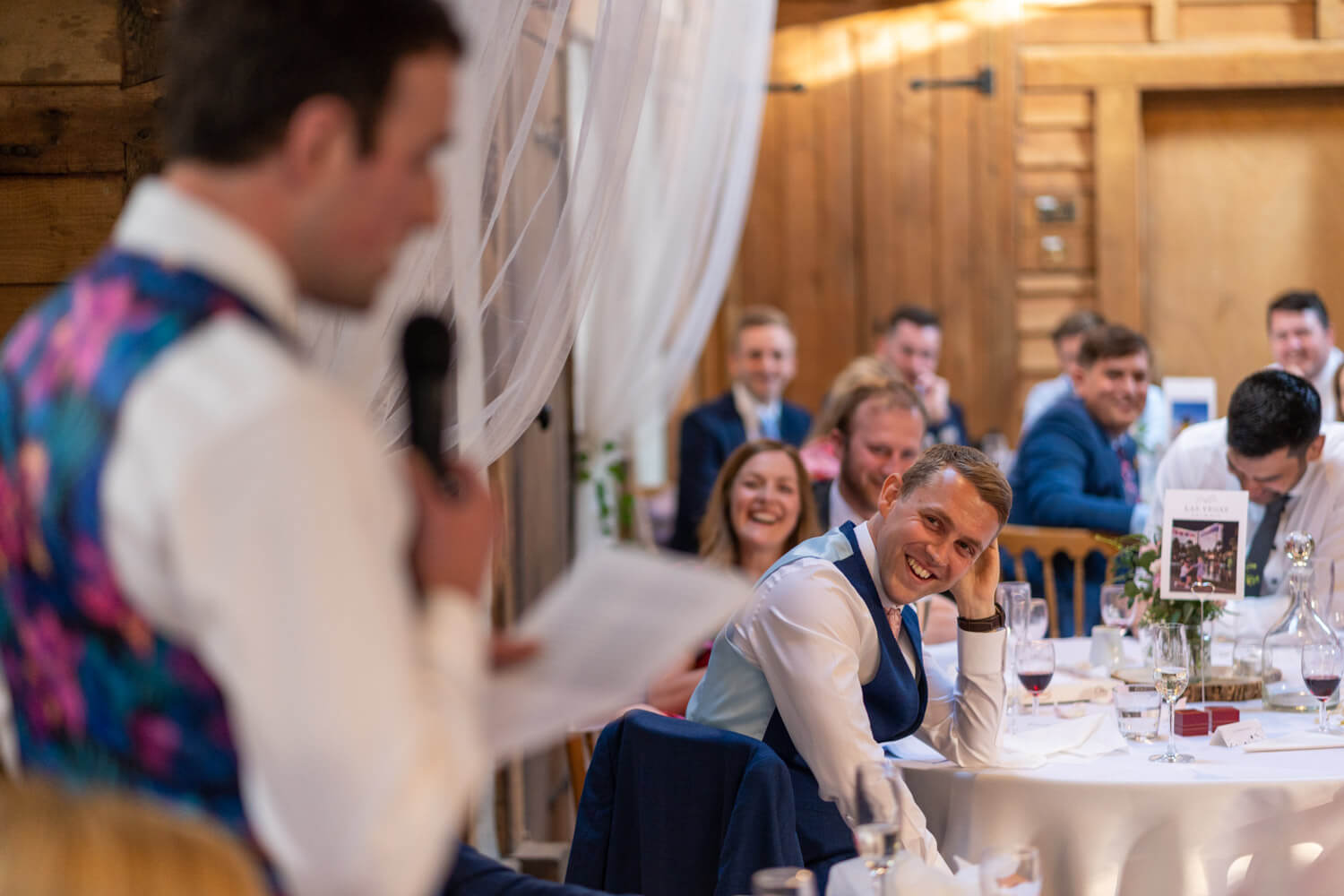 the best man laughs during the groom's speech in the Main Barn at Herons Farm