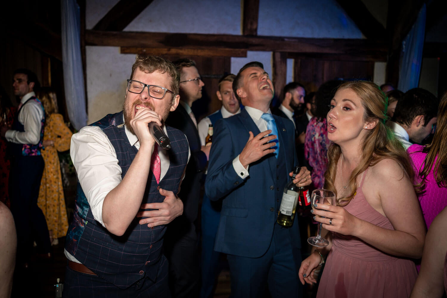 dancing wedding guests sing along with the singer on the dance floor