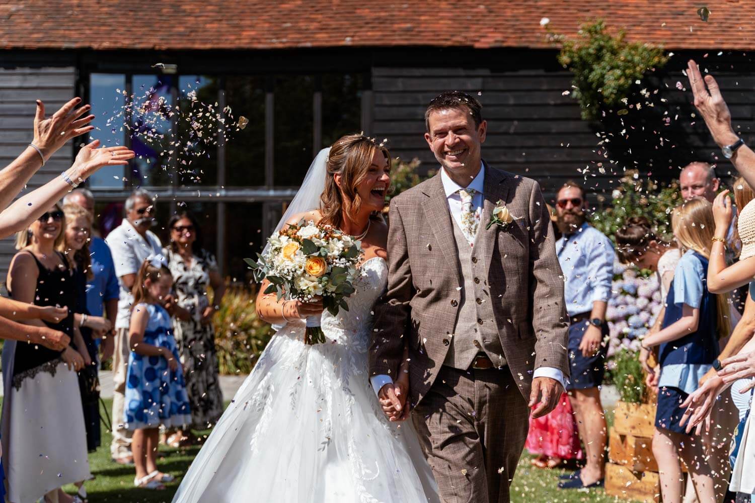 The newly married couple walk back down the aisle through confetti.