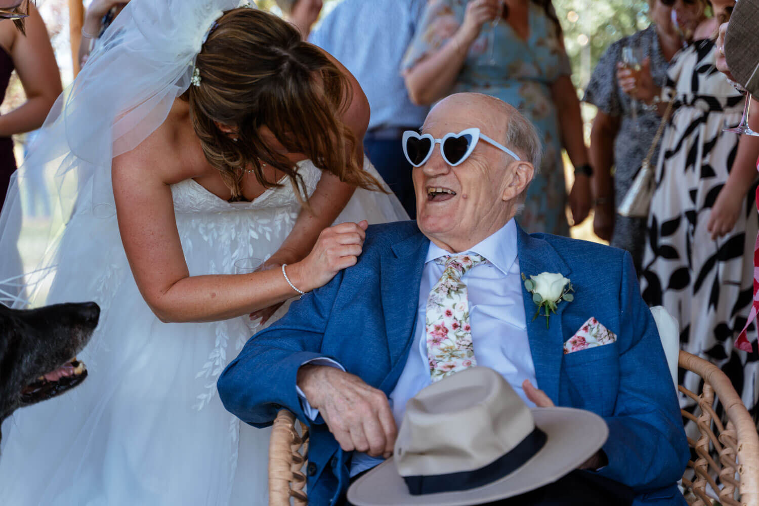 The bride laughs with a guest wearing heart shaped sunglasses after the ceremony.