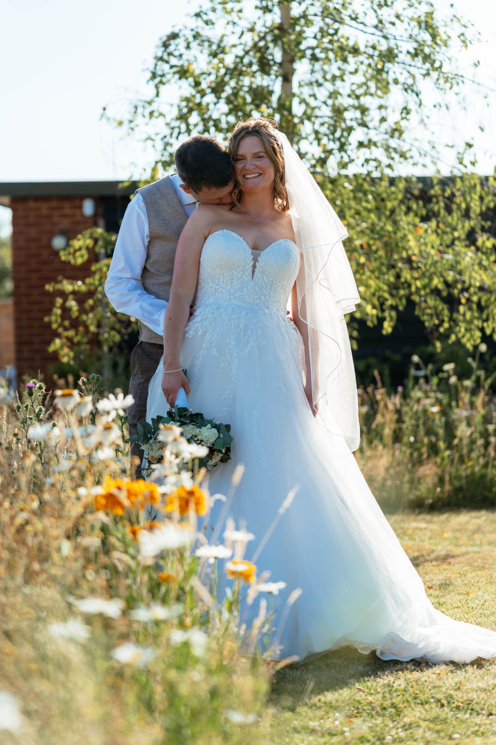 Bride and groom sharing a quiet moment among wildflowers in the golden hour light.
