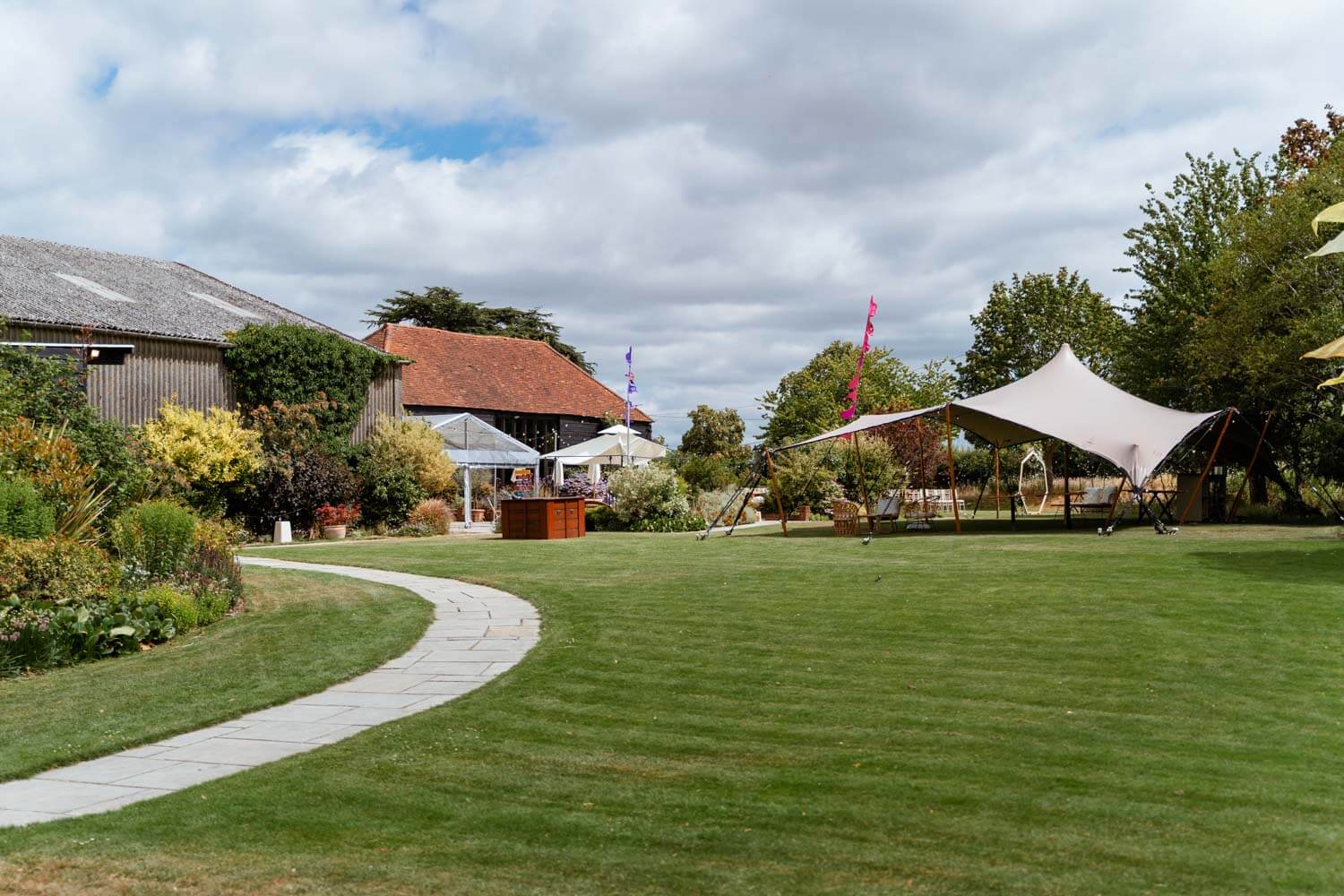 View across the lawn towards the barn and a stretch tent set up for the reception at Stokes Farm Barn.