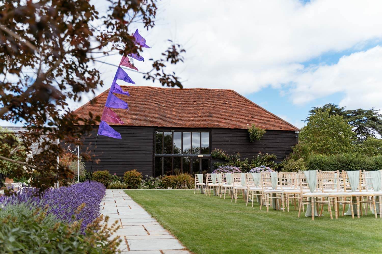 Ceremony chairs lined up on the lawn in front of the barn, bunting flags fluttering above.