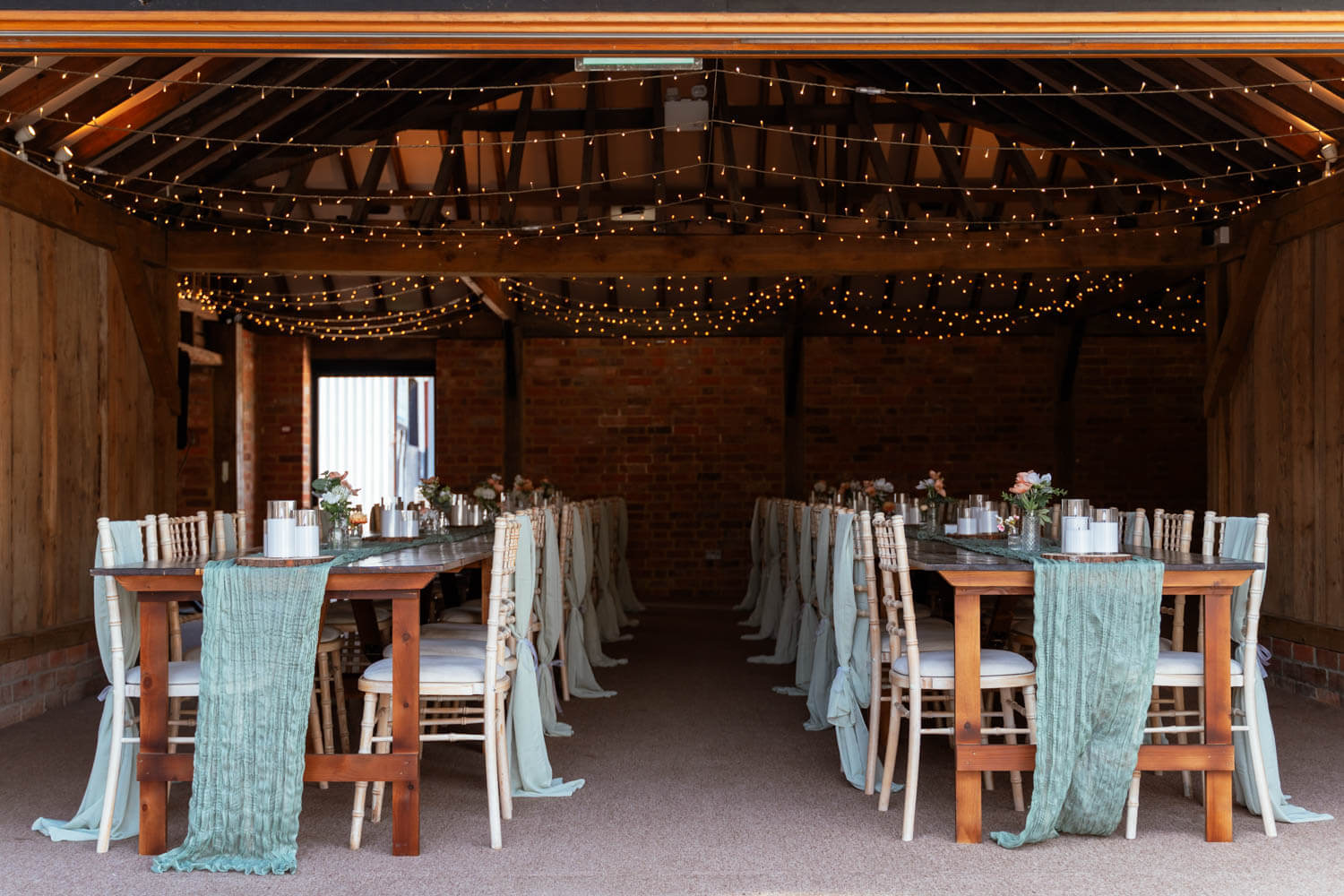 The barn's reception tables set with candles and flowers ahead of the wedding breakfast.